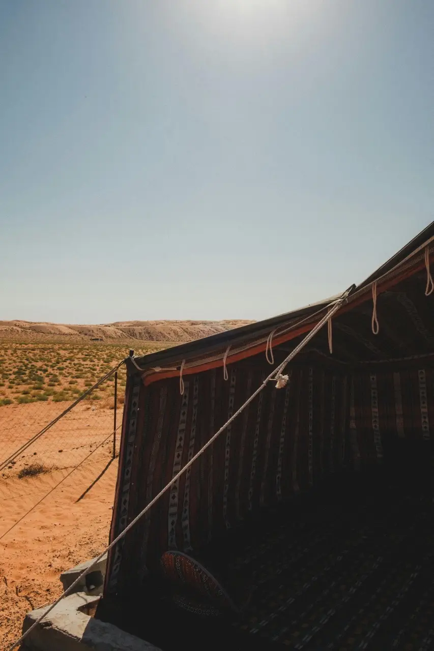 A Bedouin-style tent in the desert under a pale sky.
