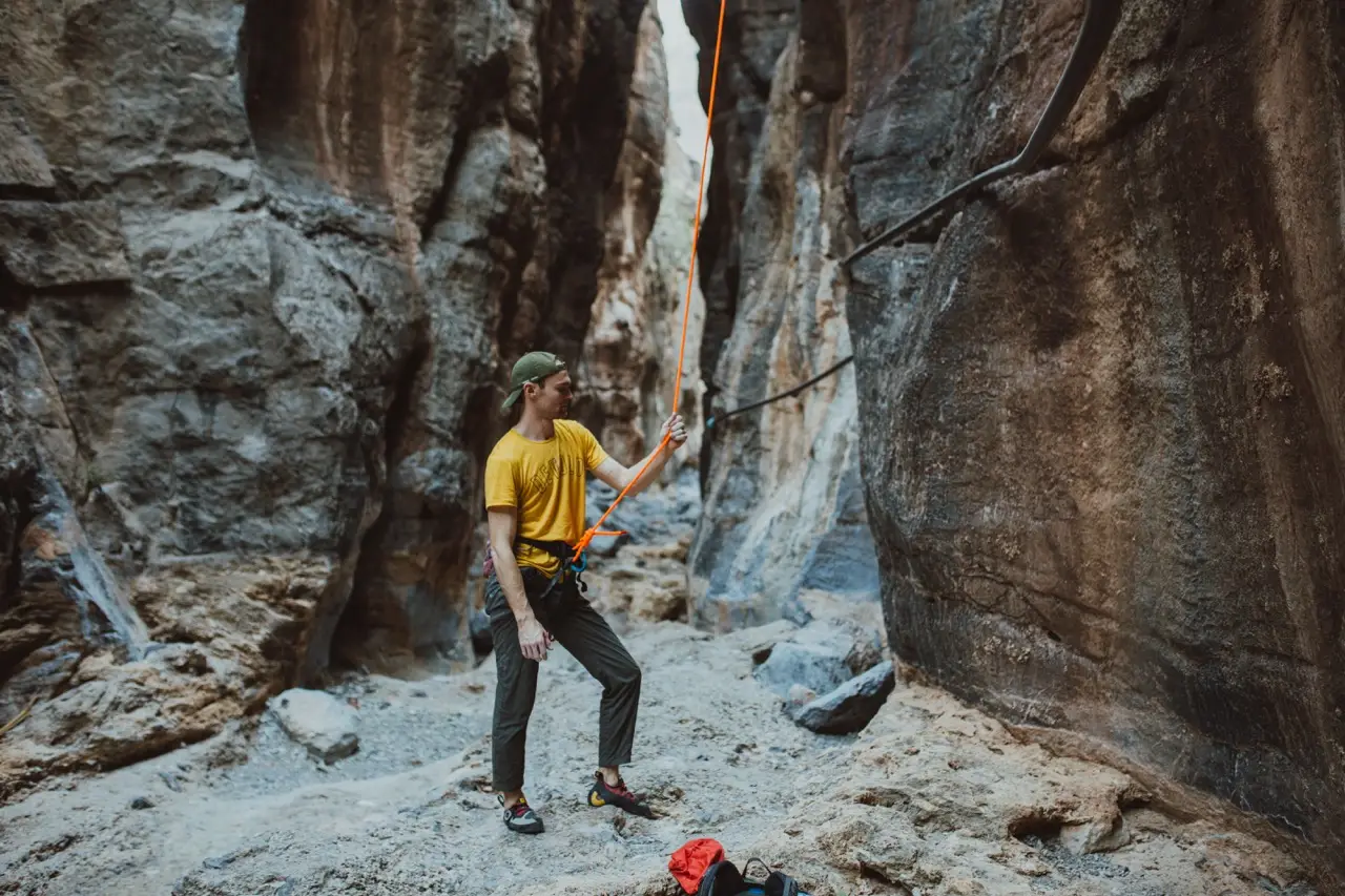 A guest in a narrow rock canyon with a climbing rope.