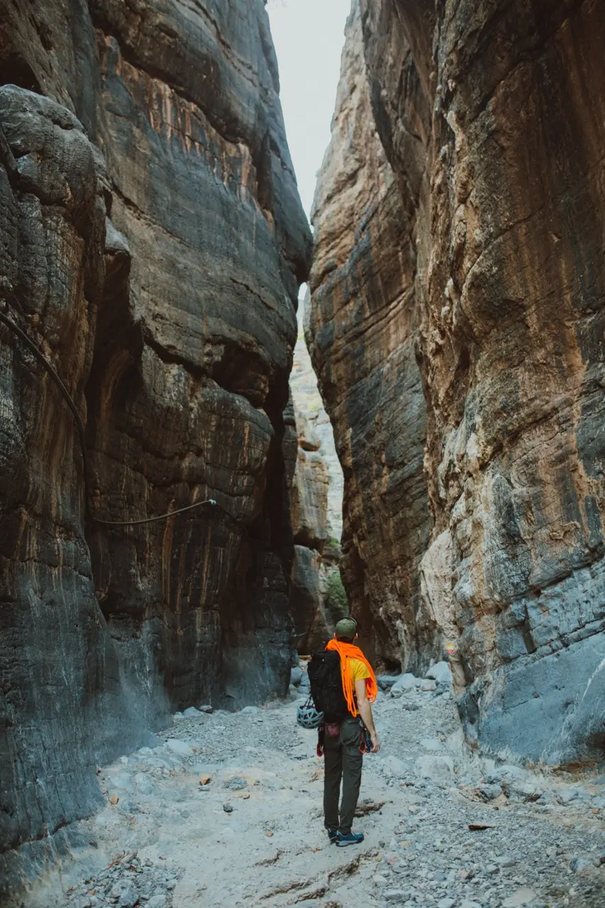 A hiker walking between the high walls of a narrow canyon.