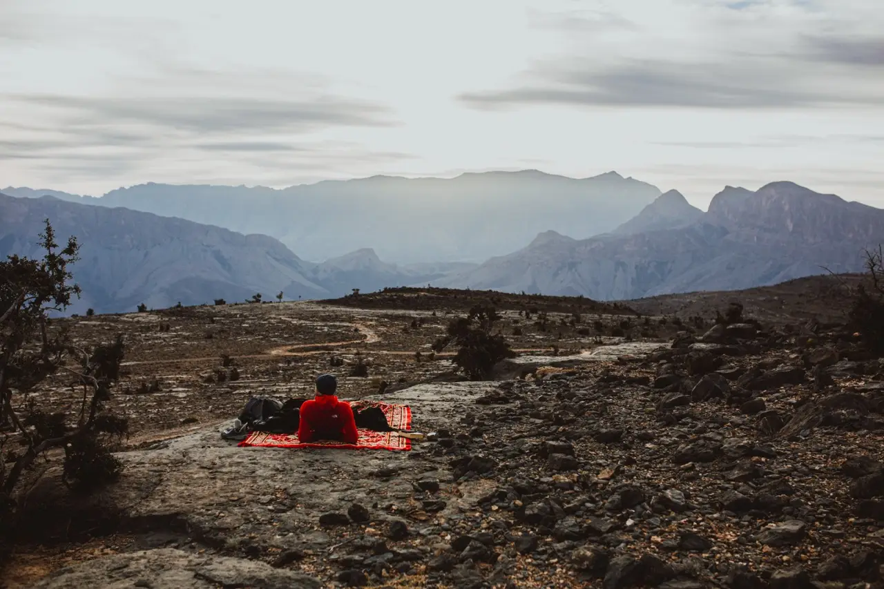 A picnic blanket on a rocky plateau, with mountain ridges in the distance.