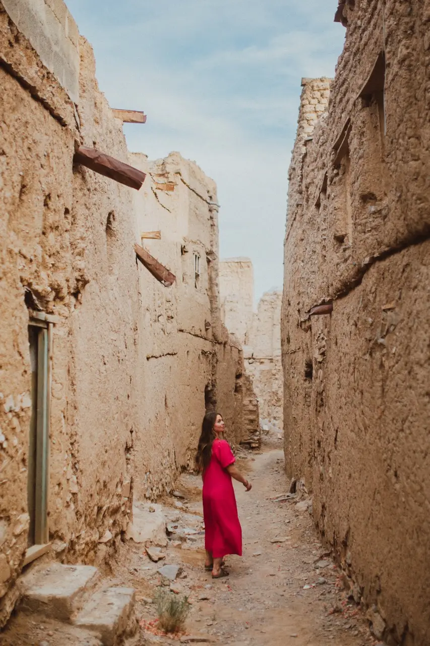 A guest walking down a lane of abandoned mud-brick houses.