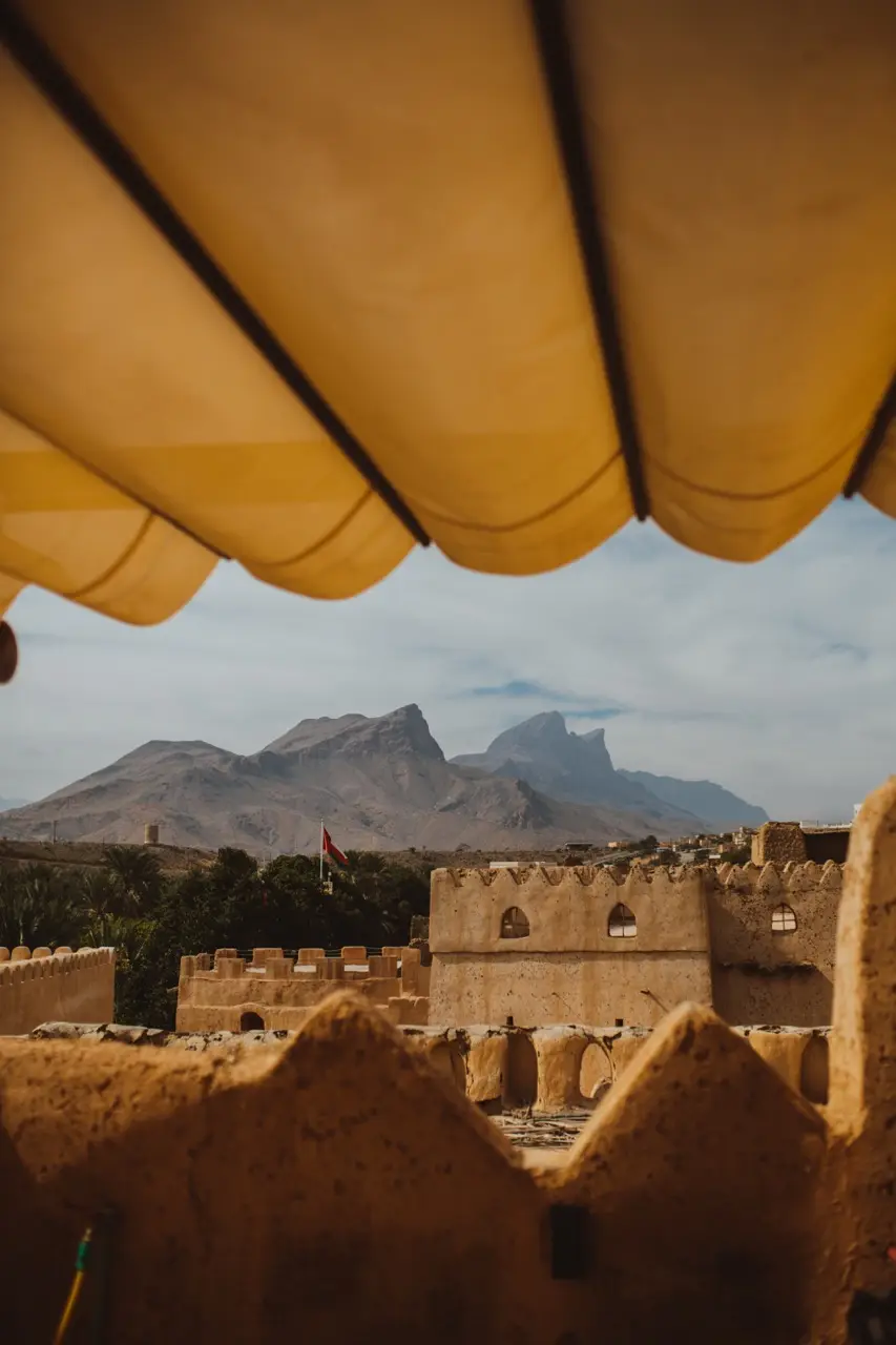 View from under a canvas awning across an old mud-brick fort to the mountains.