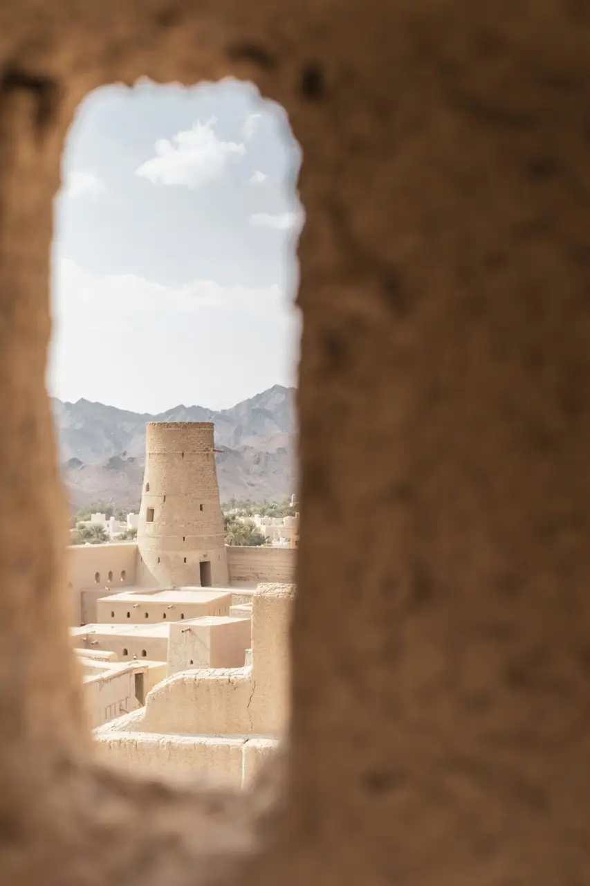 View through an old wooden window onto a stone courtyard in Oman.